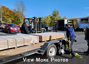 Men unloading truck bed of donated wood. View more photos.