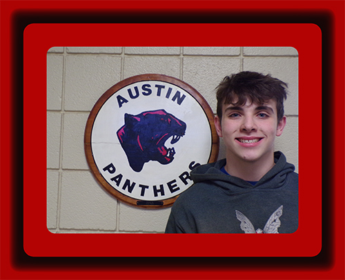 Jeff Finch, Student of the Week, standing next to the Austin Panthers logo on the wall