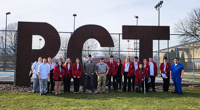 Group of proud students in front of large letters outside