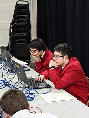 Two students at a table looking at laptops