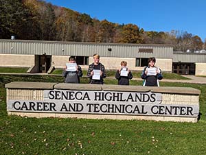 Four Seneca Highlands Career and Technical Center students with cybersecurity certificates standing behind SHCTC sign