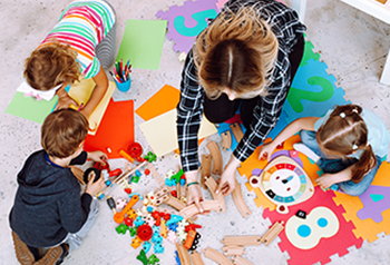 Preschool teacher working with students on the classroom floor