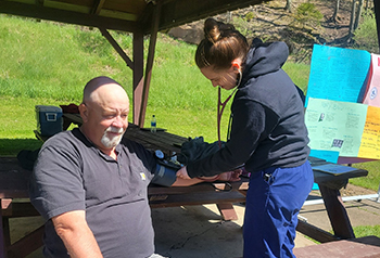 Medical assistant student taking a man's blood pressure outside