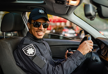 Young man smiling in a car wearing a security uniform