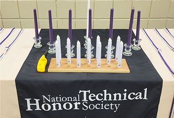 Candle on a table with a National Technical Honor Society banner